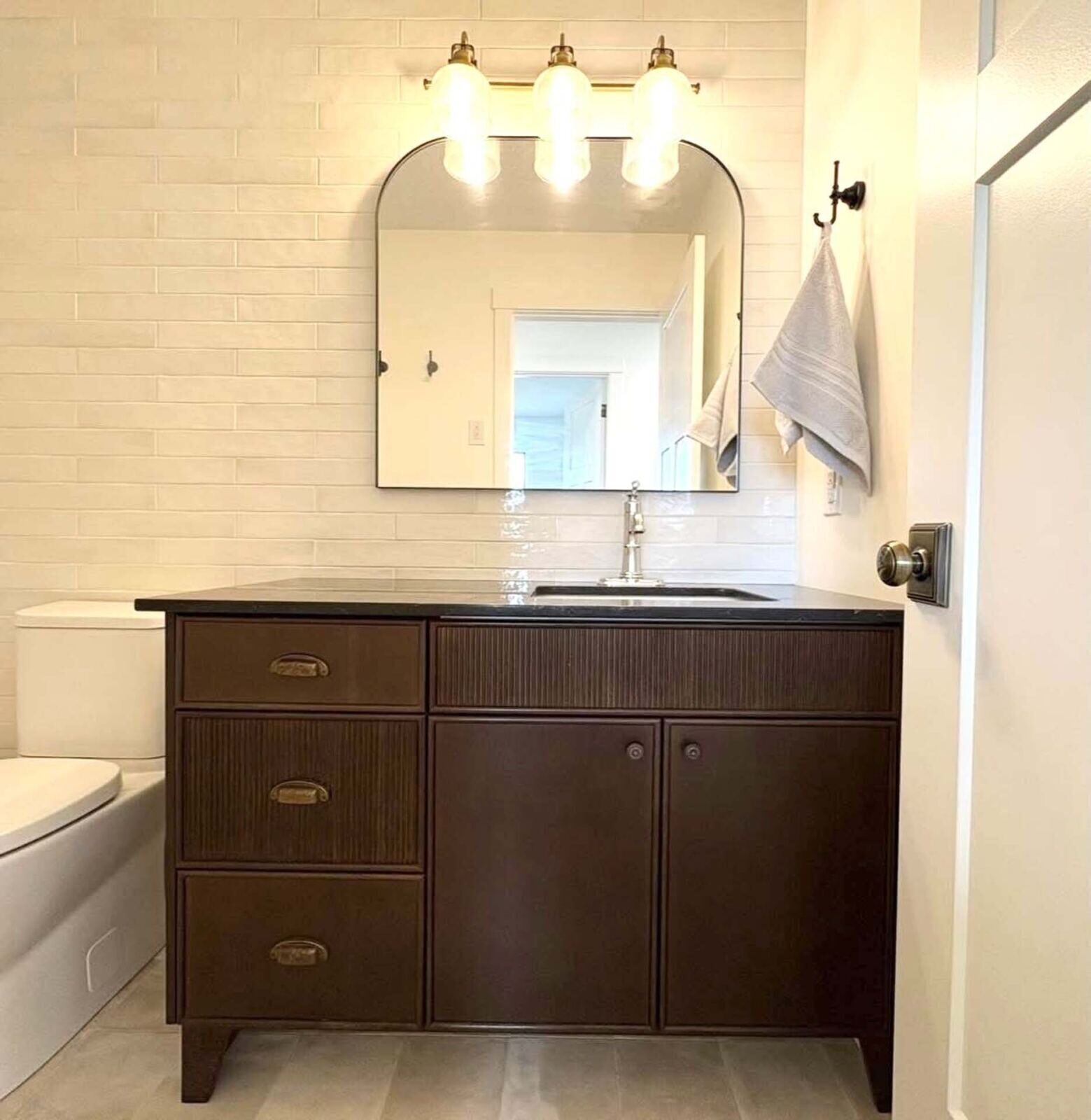 Two-handle brushed gold faucet on a dark vanity