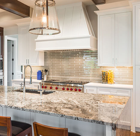 Speckled granite island in a white kitchen with a tiled backsplash