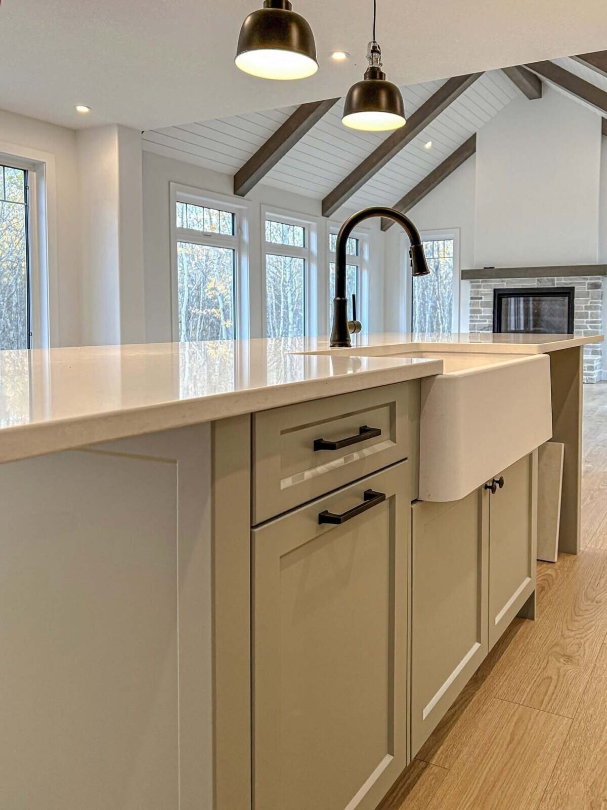 White apron-front sink set into a sage kitchen island