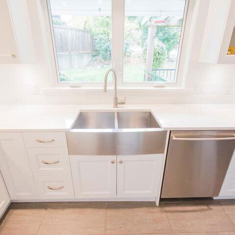 Stainless double-bowl apron-front sink in a white kitchen
