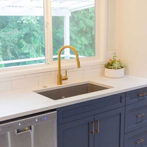Undermount sink with a gold faucet and blue cabinetry