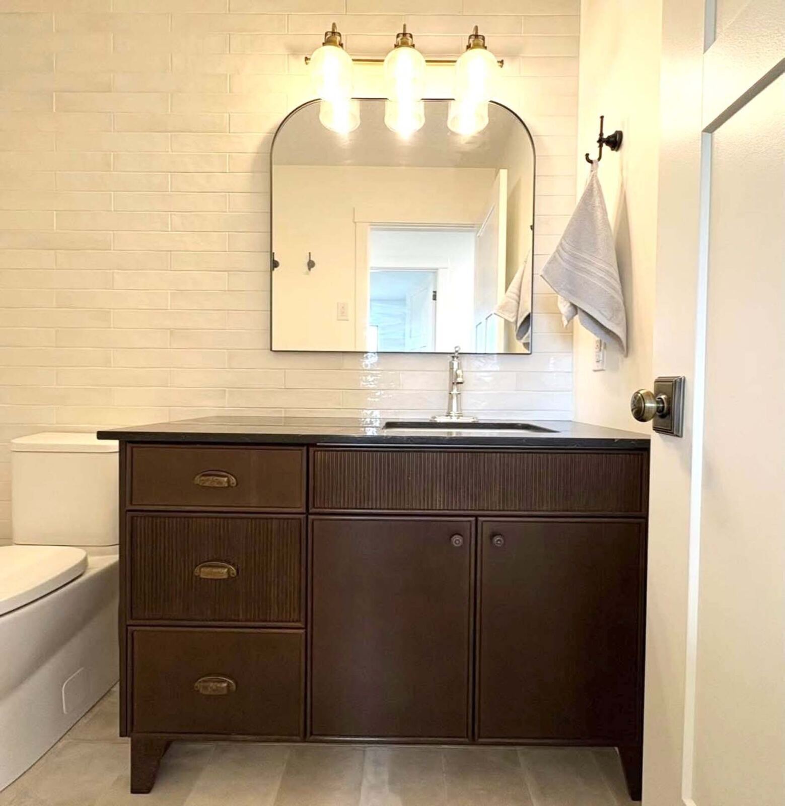 Two-handle brushed gold faucet on a dark vanity