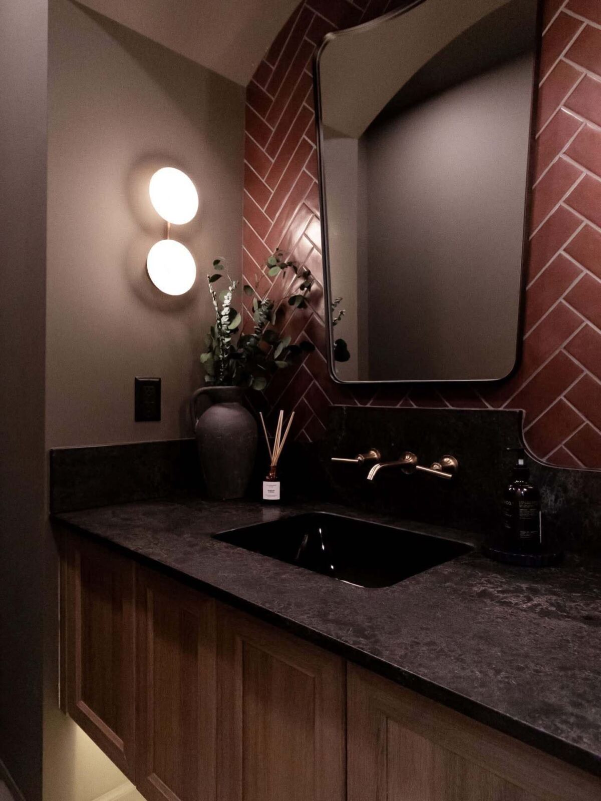 Brushed gold bath faucet against dark tile